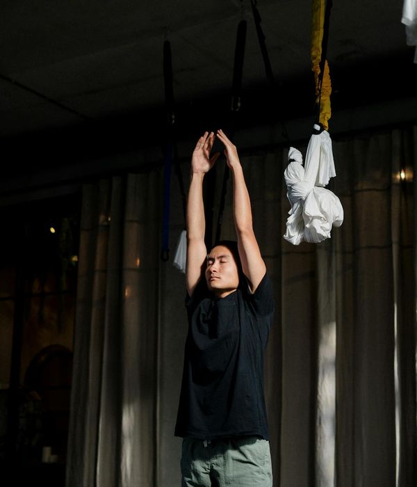 Person practicing rhythmic yoga movements in a dark studio